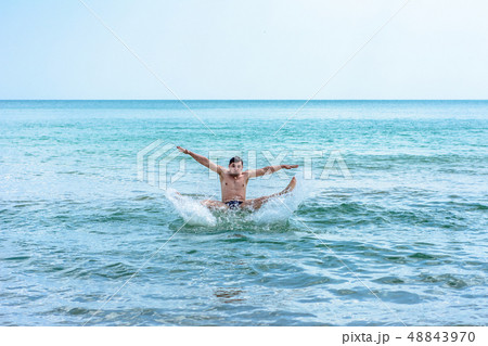 A sports man jumping over the sea waves in the 48843970