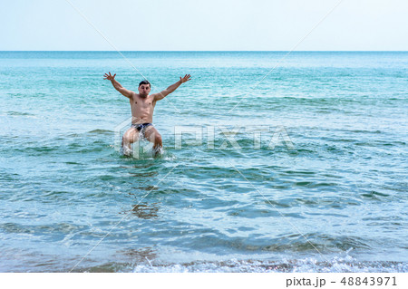 A sports man jumping over the sea waves in the 48843971