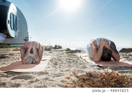 Couple of yoga professionals meditating together on sand near river Couple of yoga professionals meditating together on sand near river 48845825