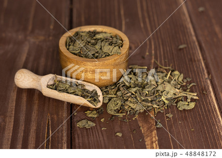Dry green tea on brown wood Dry green tea on brown wood 48848172