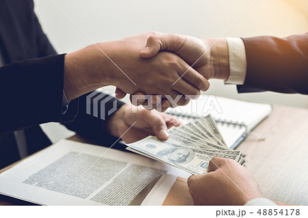 Two corporate businessmen shaking hands while one 48854178