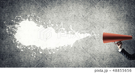 Hand of businesswoman holding red paper trumpet against concrete background 48855656