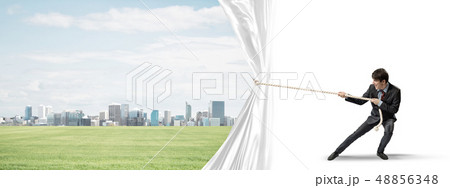 Young man opening white curtain and presenting modern city landscape 48856348