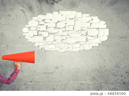 Hand of woman holding red paper trumpet against concrete background 48856500