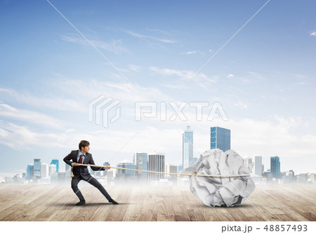 Man pulling with effort big crumpled ball of paper as creativity sign 48857493