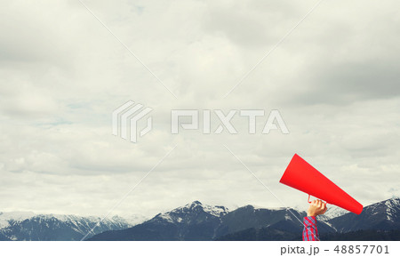 Hand of woman holding paper trumpet against natural landscape background Hand of woman holding paper trumpet against natural landscape background 48857701