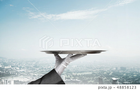 Hand presenting metal empty tray and modern city landscape at background 48858123