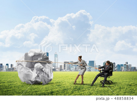 Businesspeople pulling with effort big crumpled ball of paper as creativity sign 48858834