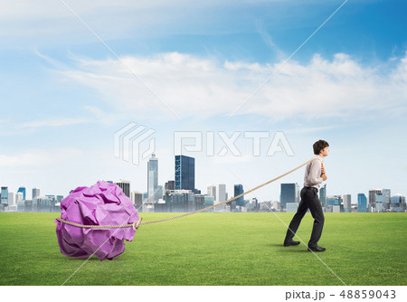 Man pulling with effort big crumpled ball of paper as creativity sign 48859043