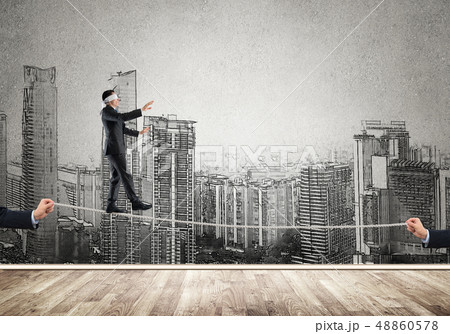 Business concept of risk support and assistance with man balancing on rope Business concept of risk support and assistance with man balancing on rope 48860578