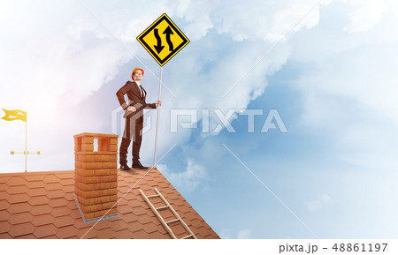 Engineer man on brick roof with sign in hands. Mixed media 48861197