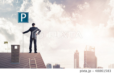 Young businessman with parking sign standing on brick roof. Mixe Young businessman with parking sign standing on brick roof. Mixe 48861583