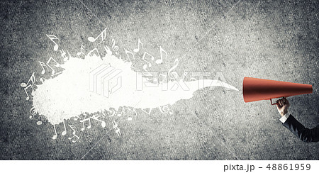 Hand of businesswoman holding red paper trumpet against concrete background 48861959