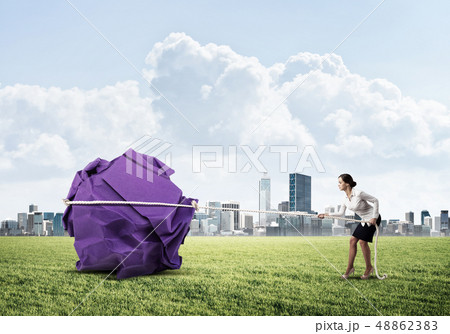 Woman pulling with effort big crumpled ball of paper as creativity sign 48862383