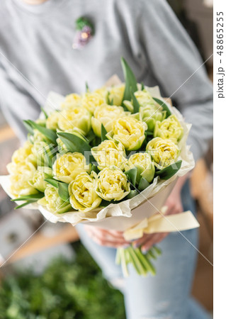 Young beautiful woman holding a spring bouquet of yellow tulips in her hand. Bunch of fresh cut Young beautiful woman holding a spring bouquet of yellow tulips in her hand. Bunch of fresh cut 48865255