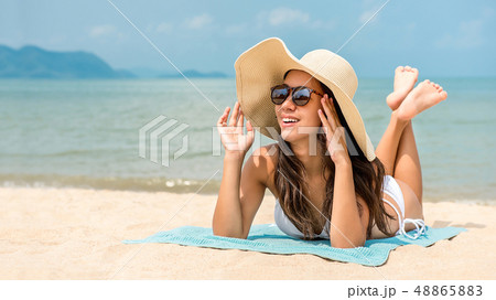 Young happy Asian woman with sunhat lying at the Young happy Asian woman with sunhat lying at the 48865883
