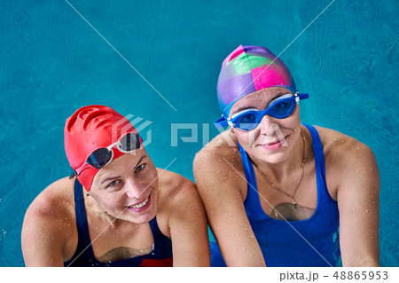 Two smiling swimmer women relaxing in the pool 48865953