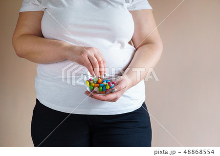 overweight woman eating unhealthy sweet candies 48868554