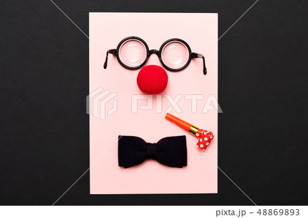 Funny glasses, red clown nose and tie lie on a colored background, like a face. Funny glasses, red clown nose and tie lie on a colored background, like a face. 48869893