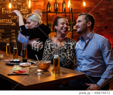 Group of friends watching tv in a cafe behind bar counter Group of friends watching tv in a cafe behind bar counter 48874072
