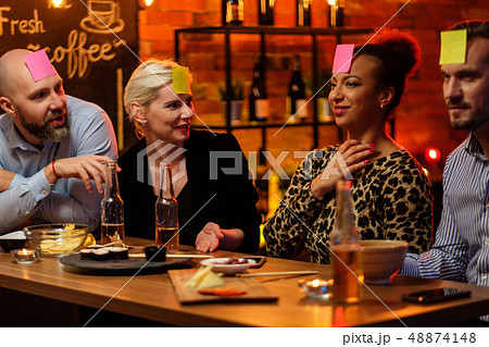 Group of friends playing sticky head game behind bar counter in a cafe 48874148