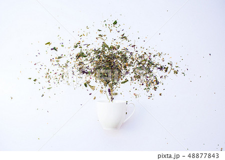 Cup and dry leaves herbal tea scattered on white Cup and dry leaves herbal tea scattered on white 48877843