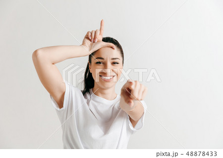 Losers go home. Portrait of woman showing loser sign over forehead Losers go home. Portrait of woman showing loser sign over forehead 48878433