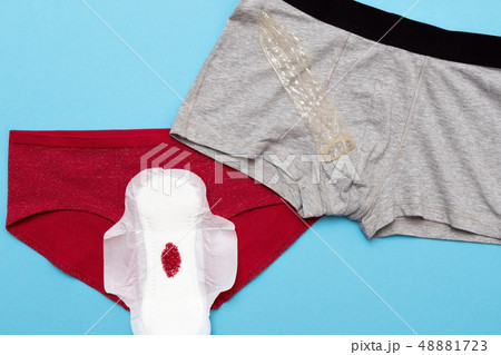 Red drop from beads on pants on blue background. Menstruation period 48881723