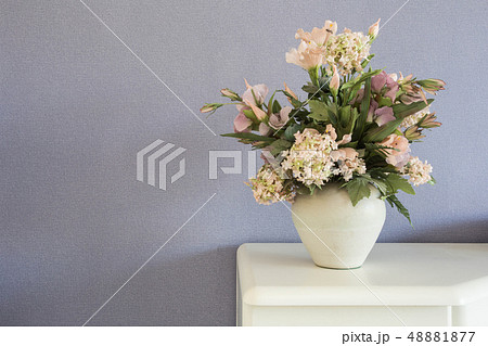 Fake flowers in white vase on the table with purple wall background texture 48881877