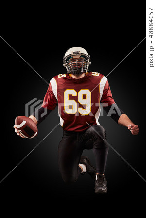 Portrait of American football player holding a ball with both his hands 48884057