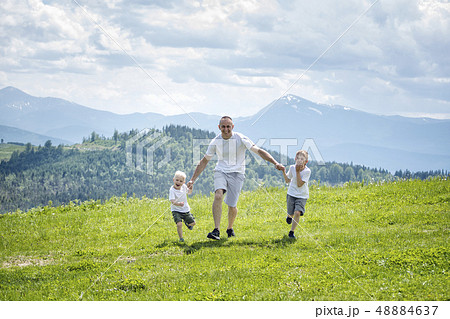 Father and two young sons running on the green Father and two young sons running on the green 48884637
