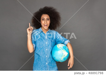 Idea for travel. Mulatto woman standing isolated on grey with terrestrial globe pointing up smiling Idea for travel. Mulatto woman standing isolated on grey with terrestrial globe pointing up smiling 48891798
