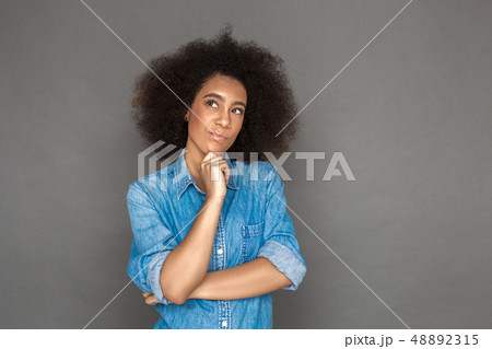Freestyle. Mulatto woman standing isolated on grey looking aside thoughtful 48892315