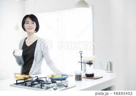ダイニングキッチンで朝食を食べる３０代女性 48893402