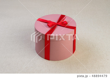 Round pink giftbox with red ribbon 48894479
