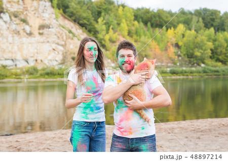 Pet, summer tourism, festival holi and nature concept - funny man and woman with cat on natural 48897214
