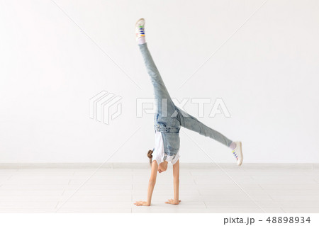 people, sport and children concept - pretty little girl doing gymnastics over white background 48898934