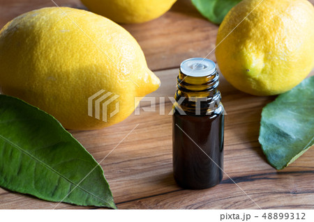 A dark bottle of lemon essential oil with fresh 48899312