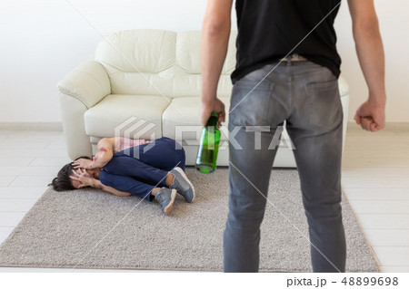Victim, domestic violence, abuse and alcoholic concept - drunk man with bottle near his wife lying 48899698