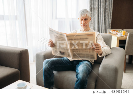 Adult man sitting on couch and reading newspaper Adult man sitting on couch and reading newspaper 48901542
