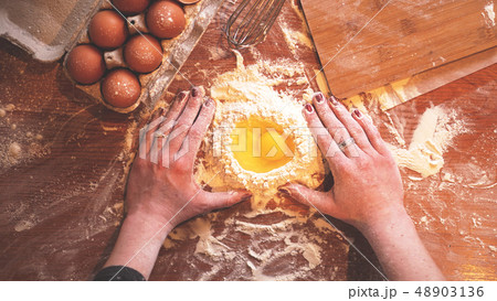 Professional female baker cooking dough with eggs and flour 48903136