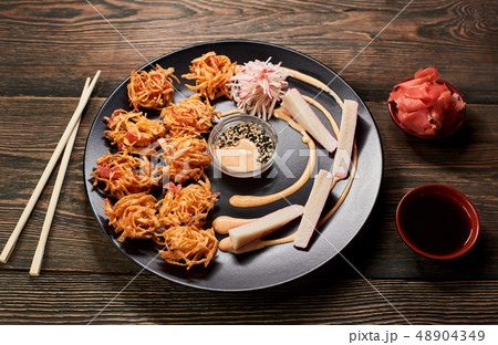 Japanese tempura roast dish serving with crab sticks, sauces and salmon. Bamboo chopsticks on dark Japanese tempura roast dish serving with crab sticks, sauces and salmon. Bamboo chopsticks on dark 48904349