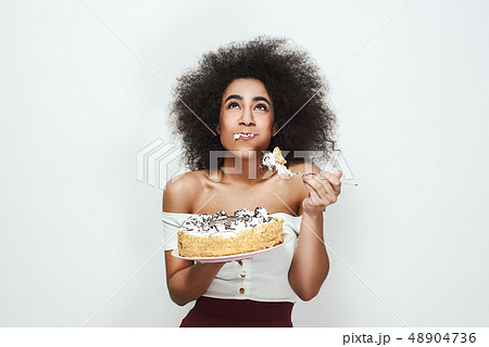 Yami! Happy young afro american woman with curly hair is eating her birthday cake. smiling and 48904736