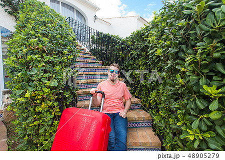 Holiday, travel and tourism concept - Handsome man with red suitcase sitting on a stairs Holiday, travel and tourism concept - Handsome man with red suitcase sitting on a stairs 48905279