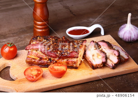 Sliced grilled pork ribs barbecue Striploin steak with chimichurri sauce and tomatoes on cutting Sliced grilled pork ribs barbecue Striploin steak with chimichurri sauce and tomatoes on cutting 48906154