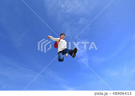 青空でジャンプする小学生の女の子（ランドセル） 48906413