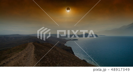 Total solar eclipse in dark red sky above sea and 48917349