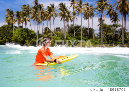 Child surfing on tropical beach. Surfer in ocean. Child surfing on tropical beach. Surfer in ocean. 48918701