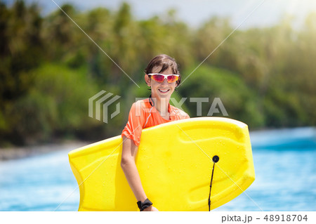Child surfing on tropical beach. Surfer in ocean. 48918704