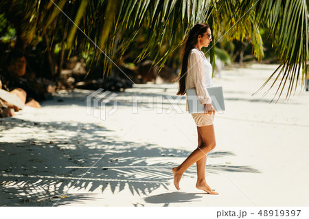 Woman travel with laptop on beach in tropics 48919397